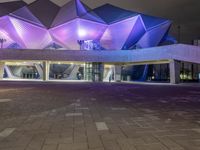 a building with three blue, white and purple lights on the side of it that appears to be an auditorium