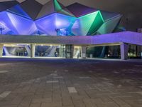 a building with three blue, white and purple lights on the side of it that appears to be an auditorium