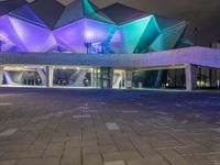 a building with three blue, white and purple lights on the side of it that appears to be an auditorium