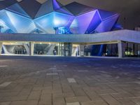 a building with three blue, white and purple lights on the side of it that appears to be an auditorium