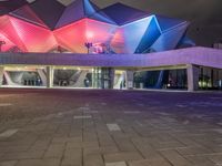 a building with three blue, white and purple lights on the side of it that appears to be an auditorium