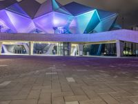 a building with three blue, white and purple lights on the side of it that appears to be an auditorium