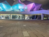 a building with three blue, white and purple lights on the side of it that appears to be an auditorium