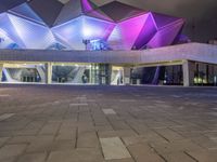 a building with three blue, white and purple lights on the side of it that appears to be an auditorium