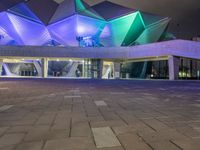 a building with three blue, white and purple lights on the side of it that appears to be an auditorium