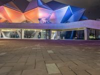 a building with three blue, white and purple lights on the side of it that appears to be an auditorium