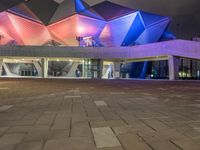 a building with three blue, white and purple lights on the side of it that appears to be an auditorium