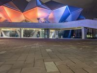 a building with three blue, white and purple lights on the side of it that appears to be an auditorium