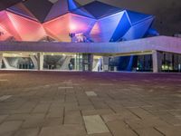 a building with three blue, white and purple lights on the side of it that appears to be an auditorium