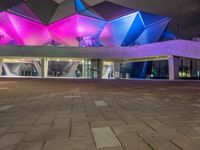 a building with three blue, white and purple lights on the side of it that appears to be an auditorium