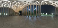 this is an image of a curved structure at night time with stairs and columns in the background