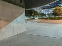 the concrete is in a wide empty space with city lights on either side and skyscrapers