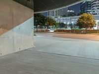 the concrete is in a wide empty space with city lights on either side and skyscrapers