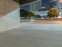 the concrete is in a wide empty space with city lights on either side and skyscrapers