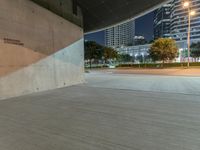 the concrete is in a wide empty space with city lights on either side and skyscrapers