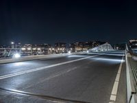 there is a street going over the bridge at night time with cars driving along it