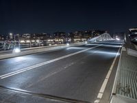 there is a street going over the bridge at night time with cars driving along it