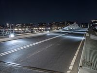 there is a street going over the bridge at night time with cars driving along it