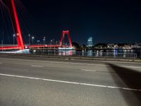 the red bridge is lit up on the street in the city by the water at night