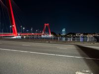 the red bridge is lit up on the street in the city by the water at night