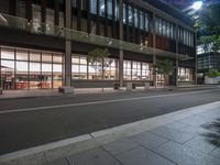 the empty road in front of a building in the dark at night time is empty