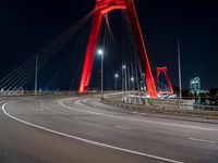 a red colored light in the night near a bridge at night, with a road on which is white lines