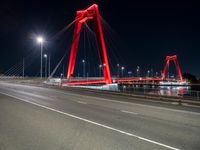 a red colored light in the night near a bridge at night, with a road on which is white lines