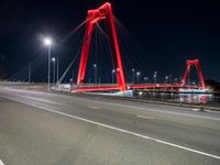 a red colored light in the night near a bridge at night, with a road on which is white lines