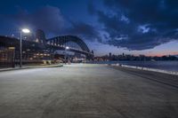 the bay bridge is lit up at dusk in sydney, australia with a bench and lamp