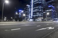 a street in a city with tall buildings lit up at night near a streetlight