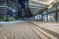 an empty sidewalk next to tall buildings in the city at night time as if for walking along them