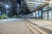 an empty sidewalk next to tall buildings in the city at night time as if for walking along them