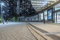 an empty sidewalk next to tall buildings in the city at night time as if for walking along them