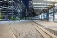 an empty sidewalk next to tall buildings in the city at night time as if for walking along them