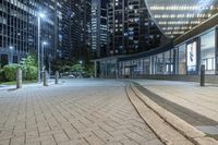 an empty sidewalk next to tall buildings in the city at night time as if for walking along them