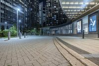 an empty sidewalk next to tall buildings in the city at night time as if for walking along them