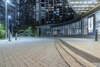 an empty sidewalk next to tall buildings in the city at night time as if for walking along them