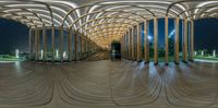 this is an image of a curved structure at night time with stairs and columns in the background