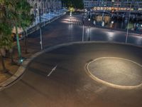 an intersection at night, with a boat in the background and some buildings on the other side