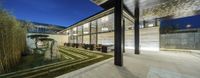 a courtyard at night with seating and lush lawns around the glass windows and bamboo plants