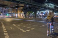 a man is riding his bicycle at night on an empty street with traffic lights on