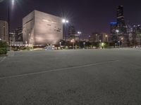 a nighttime view of a large city from the road area with empty parking lot and skyscrapers at the back