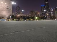 a nighttime view of a large city from the road area with empty parking lot and skyscrapers at the back