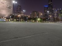 a nighttime view of a large city from the road area with empty parking lot and skyscrapers at the back