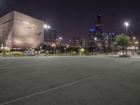 a nighttime view of a large city from the road area with empty parking lot and skyscrapers at the back