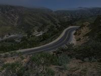 a road winding through the mountains and on top of it is a hill at night