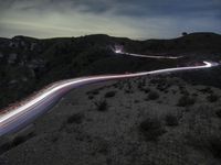 a long road is driving up the side of a mountain at night with lights from multiple vehicles