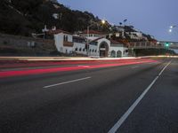 a car drives by a large white building and hill with many houses on it at night