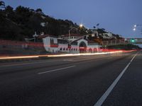 a car drives by a large white building and hill with many houses on it at night