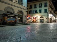 a street with two buildings and no traffic at night and one has a red traffic light